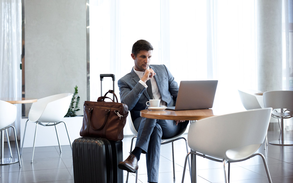 Businessman,Sitting,In,Airport,Business,Lounge,And,Looking,At,Laptop